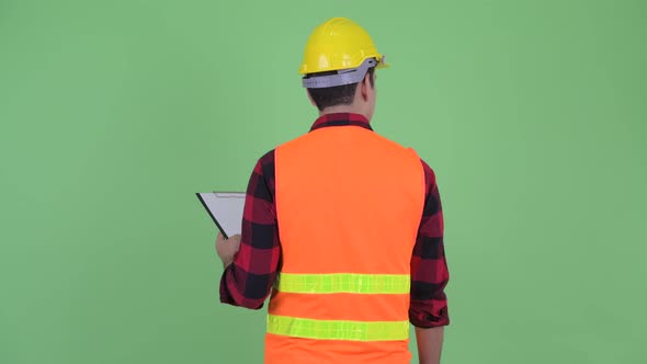 Rear View of Young Multi Ethnic Man Construction Worker Holding Clipboard