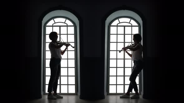 Girl Plays the Violin in the Evening Against the Background of a Window