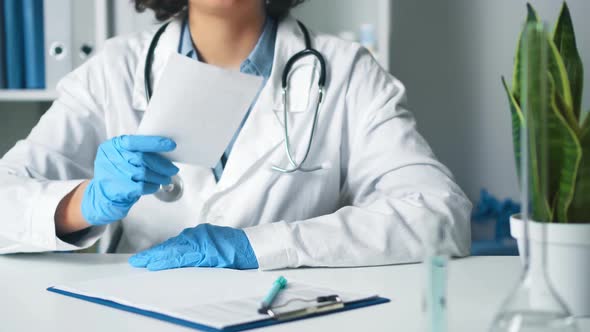 Woman Doctor In A Medical Office Holds A Paper In Her Hand, A Prescription. Medical Doctor's Hand