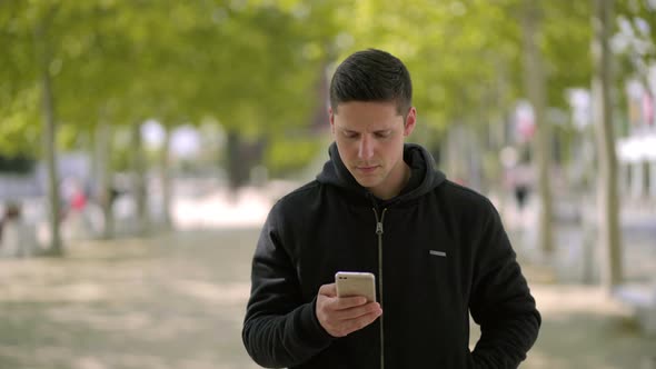 Man Using Smartphone and Walking on Street