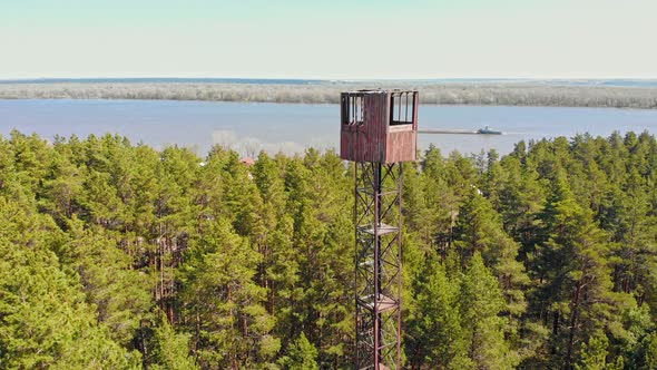 High Landmark Tower Building in the Forest - a Barge Sails on the Background