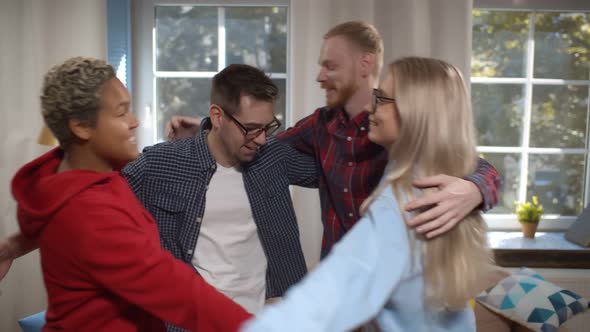 Smiling Group of Friends Laughing and Embracing Together at Home