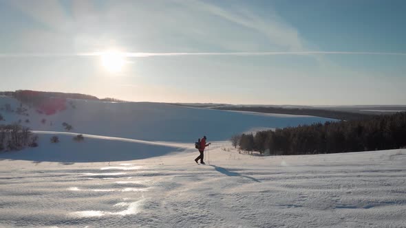 Aerial View Young Man Hiking on Top of Snowy Mountain at Beautiful Winter Sunset. Male Mountaineer