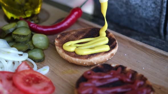 Making Burger  Spreading the Mustard Sauce on a Half of Grilled Burger Bun