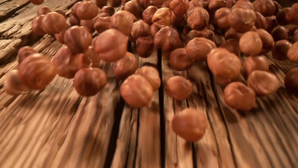 Super Slow Motion Detail Shot of Hazelnuts Rolling Towards on Wooden Background at 1000Fps