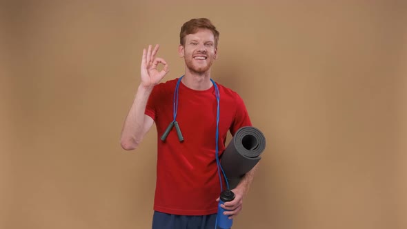 Cheerful Young Man Says Ok Shows Okay Gesture in Sportswear Promotes Healthy Lifestyle Isolated on