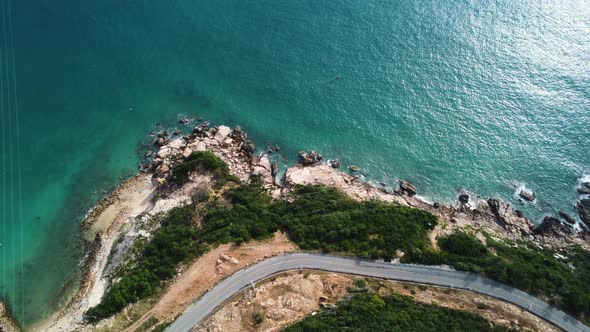 Aerial top down, road next to ocean coast with blue turquoise water. Small tide rolling in