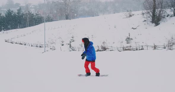 Male Snowboarder Rides on a Board in the Snow From the Ski Slope in Slow Motion