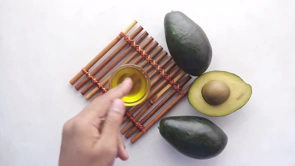 Oil and Slice of Avocado on White Background Top View