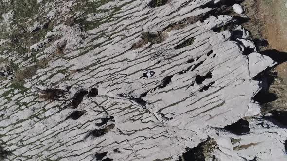 Caucasian person laying down on rugged rough landscape looking up at sky, spinning descending aerial