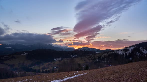 an epic sunset with beautiful warm colors, moving colorful clouds over the snow-capped mountains