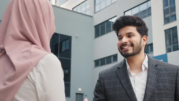 Muslim Businessman and Woman in Hijab Shaking Hands to Each Other While Standing