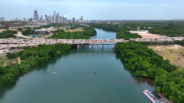 Paddleboarders on Colorado River with Austin Texas skyline panorama in distance. Cars travel on brid