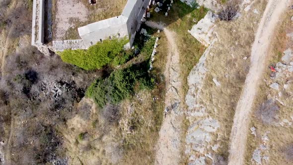 drone shot of a mountain biker riding on a gravel road away from a ruin castle