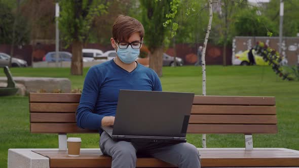 Young professional freelancer man wearing a surgical face mask, working on laptop