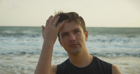 Portrait of a Young Caucasian Man Looking Into the Camera Along the Backdrop of the Beautiful Sea