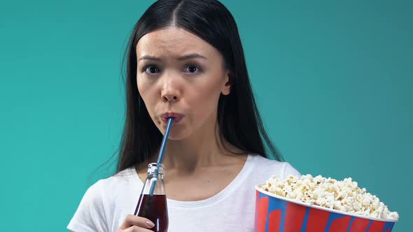 Asian Girl With Pop Corn and Sweet Beverage Watching Scary Movie, Close-Up