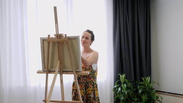 Young talented woman drawing on canvas in art home studio