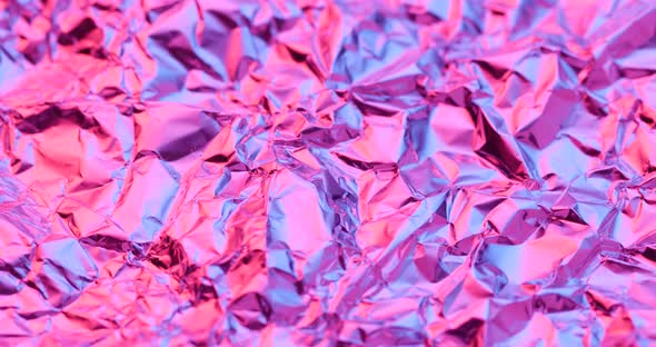 Wrinkled aluminum foil under red and purple lighting in rotation