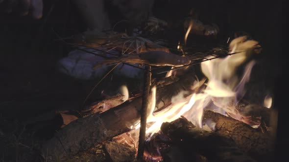 Hands of young man putting shrimps on the grill are cooked on fire, Cook at camping.