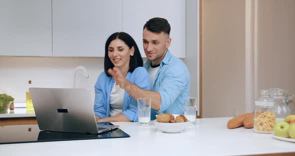 Married Couple Waving Hands to their Friend or Relative Via Computer Video chat During Bbreakfast