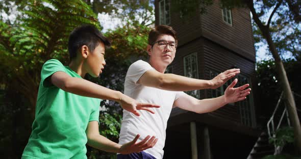 Happy asian fother exercising in garden with sonr, practicing tai chi together