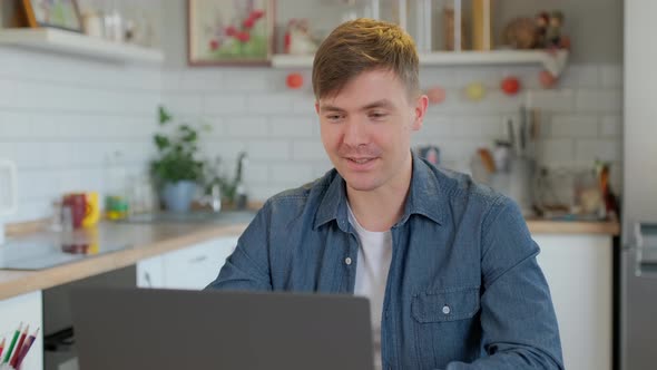 Smiling business man talking on video conference online at home. Handsome worker having video call