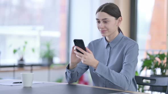 Attractive Young Latin Woman Using Smartphone at Work