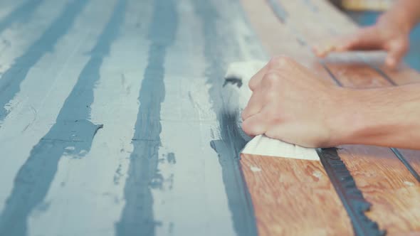 Male hands ring masking tape after sealing timber roof of wooden boat