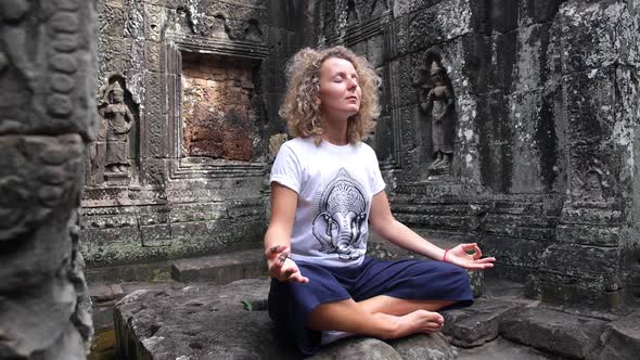 Woman Meditating in Ancient Temple Of Angkor Wat