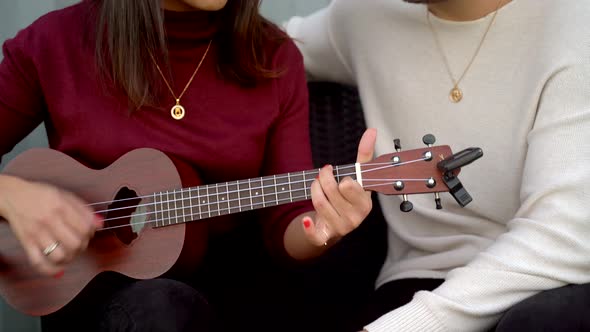 Couple playing ukulele on terrace of compact house