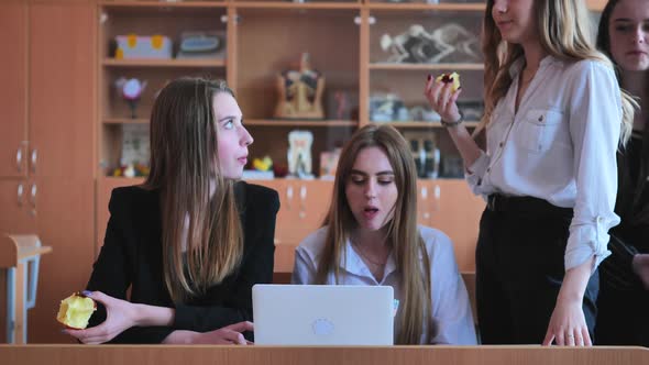 Schoolchildren Friends Working Together in Class with a Laptop and Eating Apples