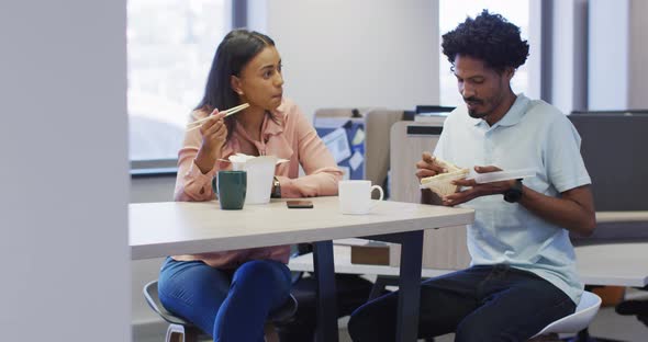 Video of happy diverse businesswoman and businessman eating and talking in office