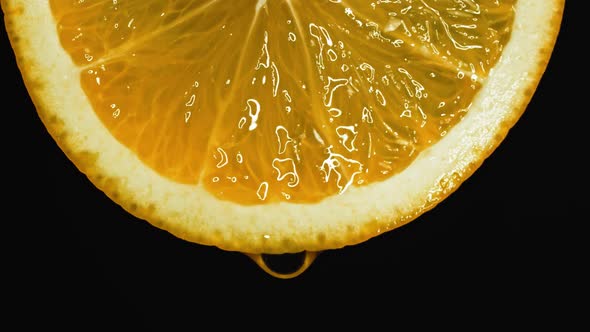 A Drop of Pure Water or Juice Dripping From a Slice of Orange