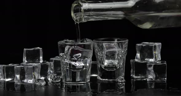 Pouring Up Two Shots of Vodka From a Bottle Into Glass Black Background