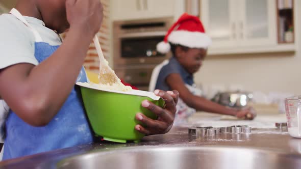 African american boy and girl wearing aprons baking together in the kitchen at home