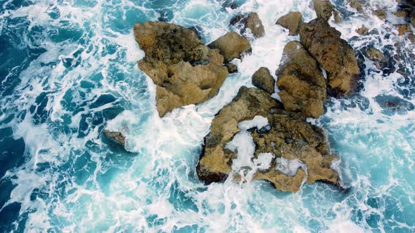 Sea Waves Washes the Rocky Shore Above Aerial Shot Flying Over Coastline Cliffside with Blue Pure