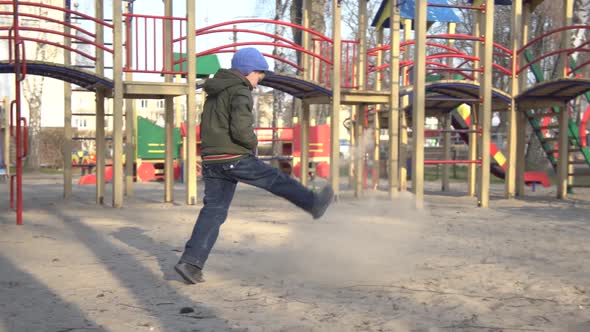 Wide Shot of Upset Caucasian Little Boy Spending Spring Day Alone on Playground. Side View of