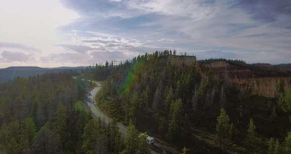 Aerial video as cars drive along a winding highway near green pines (Zion National Park, Utah)