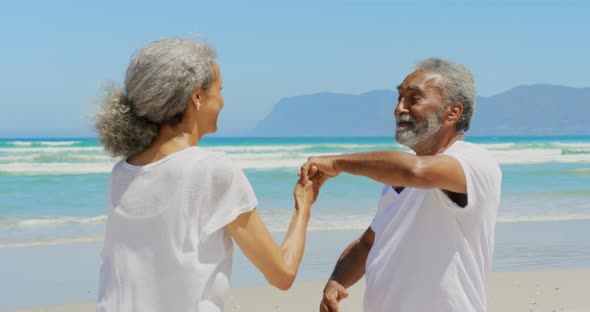 Front view of romantic active senior African American couple dancing together on the beach 4k