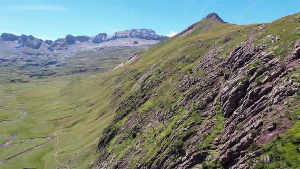 Large steep rock walls with a meandering river in the valley between the large mountains of Valle de