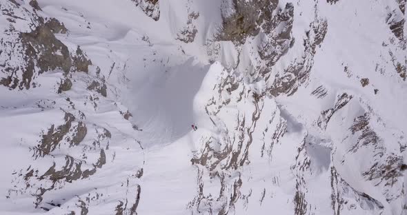 Aerial drone view of a skier skiing down a steep snow covered mountain.