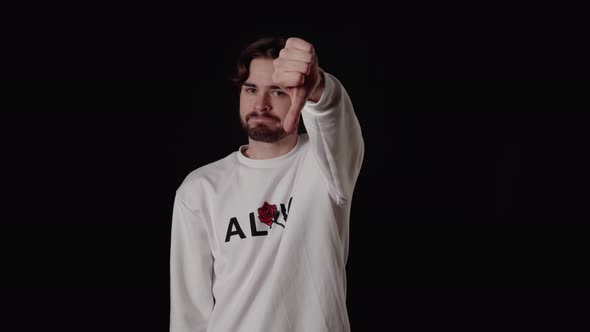 Trendy Young Man giving thumbs down, disapproving gesture, wide, black background