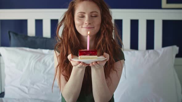 Zoom out video of woman blowing a birthday candle