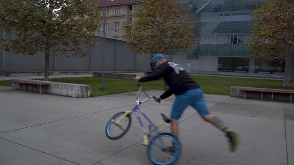 Guy riding a BMX bike in a skatepark, performing the Gyrator trick.