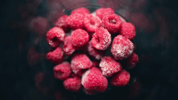 A Pile of Frozen Raspberries is Quickly Defrosted in a Glass
