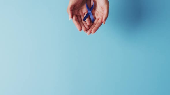 Video of biracial female doctor holding blue colon cancer ribbon