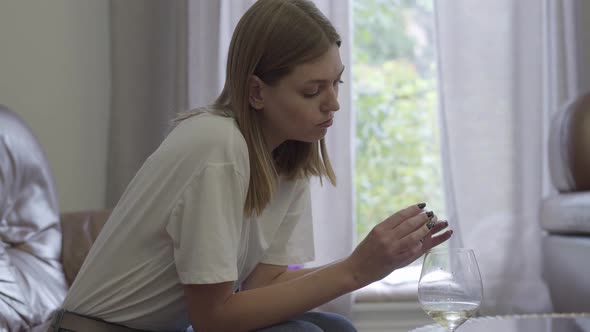 Sad Woman Holding Wedding Ring Under the Wine Glass