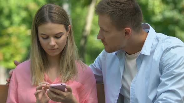 Young Man Trying to Reconcile and Hugging Girlfriend Using Phone, Ignoring Him