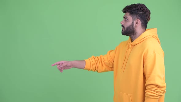 Profile View of Happy Young Overweight Bearded Indian Man Pointing Finger